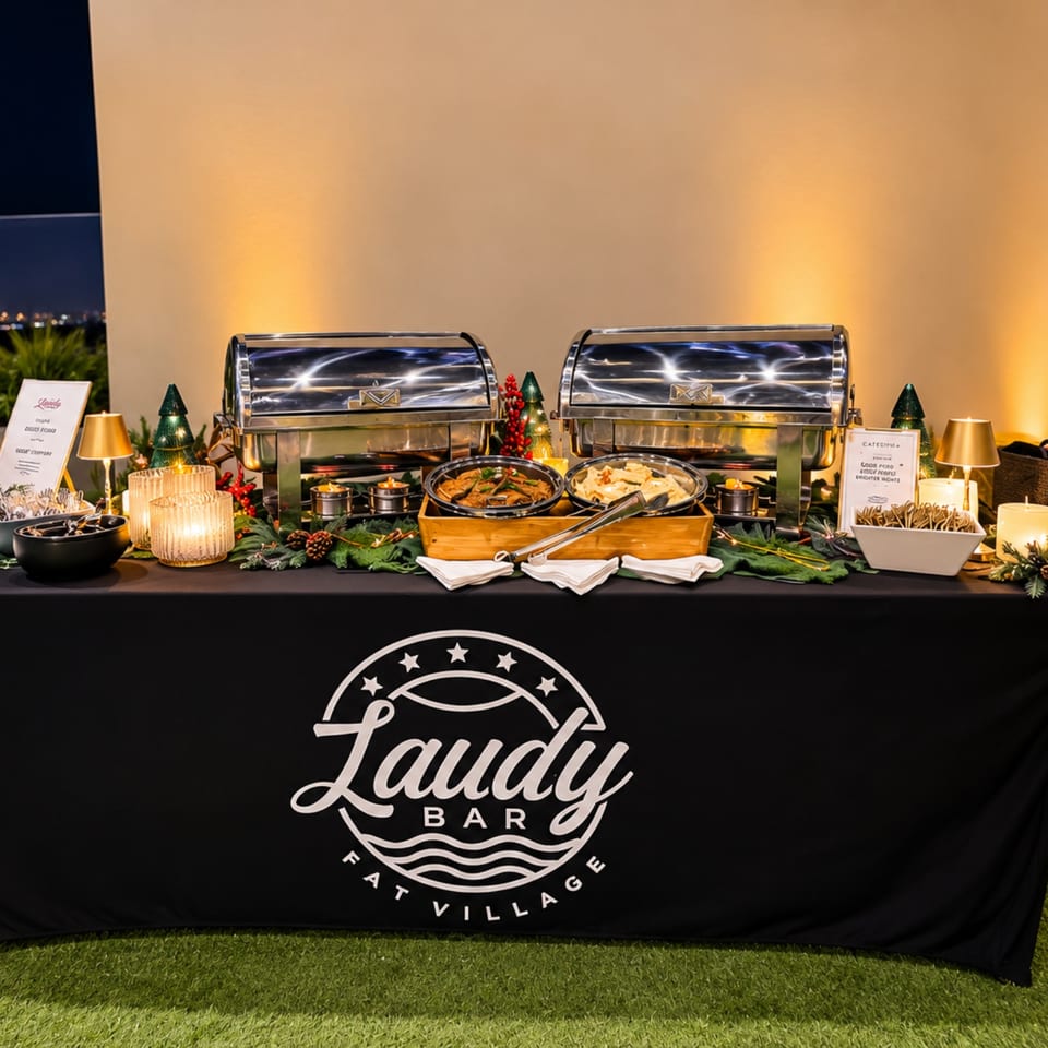 Lady Bar buffet table with chafing dishes, plated food, festive Christmas decorations, candles, and branded tablecloth.
