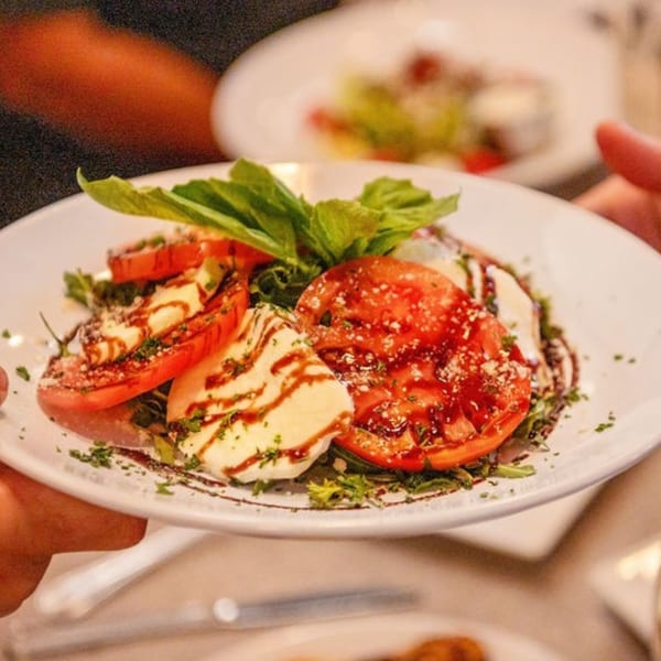 A Laudy Bar Craft Kitchen Caprese salad with sliced tomatoes, mozzarella, basil, and balsamic glaze.